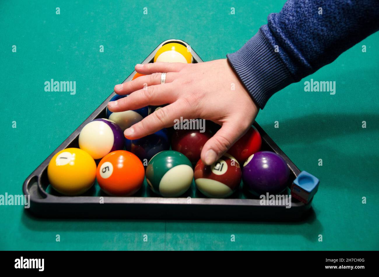 Billardkugeln auf dem grünen Billardtisch mit der Hand eines Spielers über ihnen Stockfoto