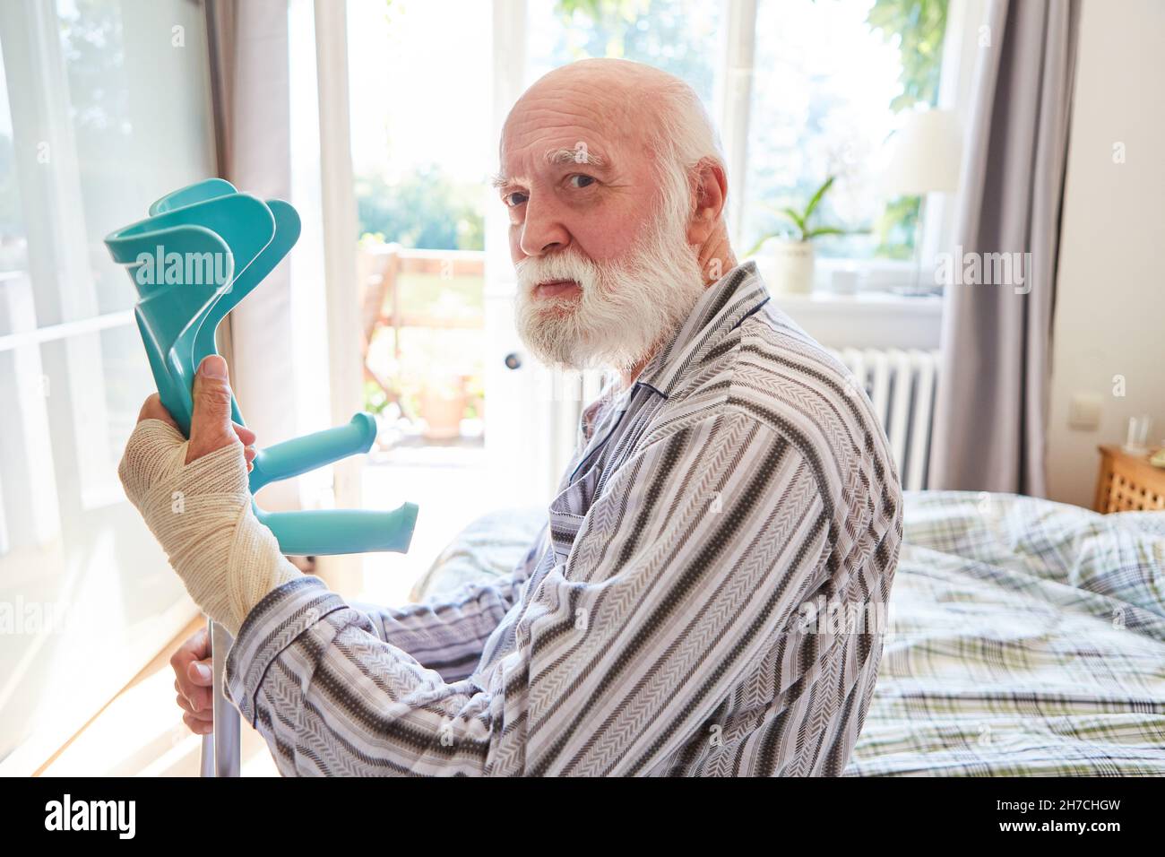Alter Senior mit gebrochenem Handgelenk und Gehhilfe in der Klinik für Reha Stockfoto