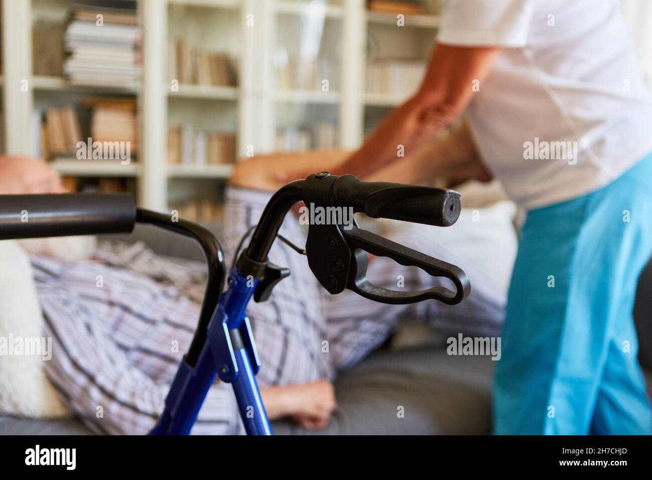 Rollator im Wohnzimmer von Senioren mit Behinderung und Physiotherapeut im Hintergrund Stockfoto