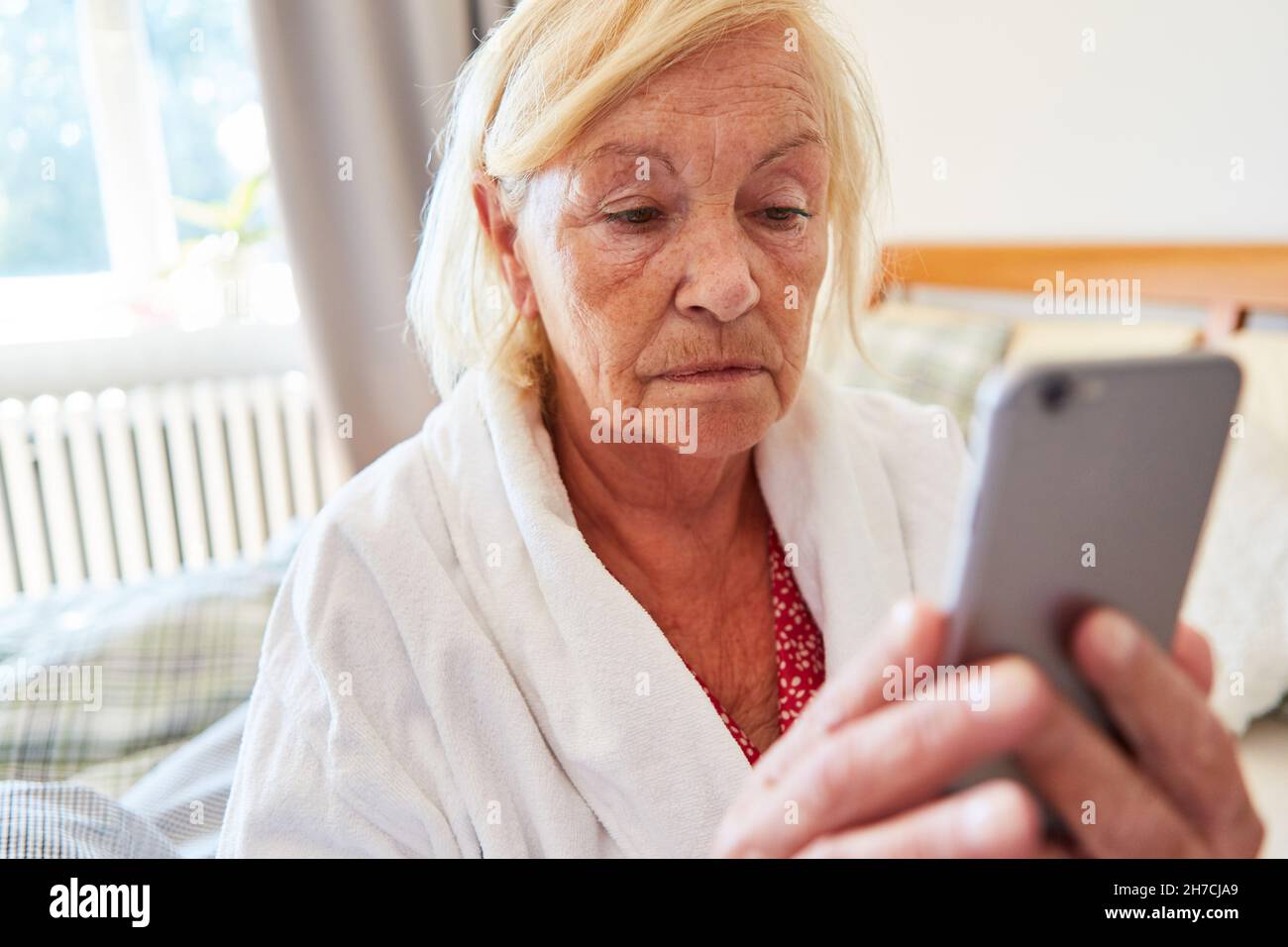 Einsame und traurige ältere Frau im Pflegeheim Video-Chat mit der Familie auf dem Smartphone Stockfoto