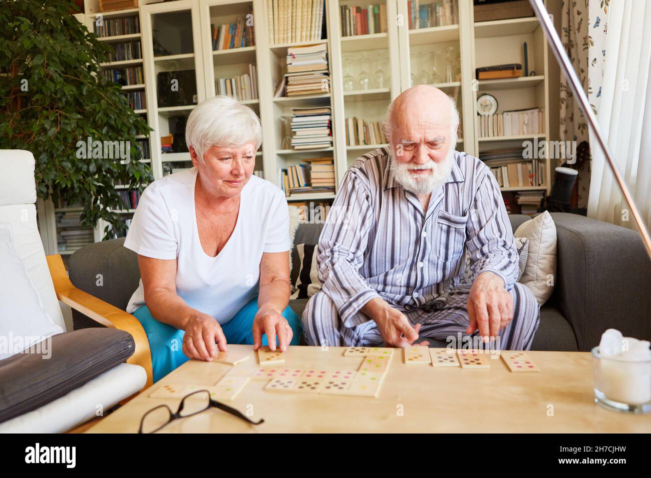 Zwei Senioren spielen in einem Seniorenheim als Gedächtnistraining und Gehirnteaser zusammen Dominos Stockfoto