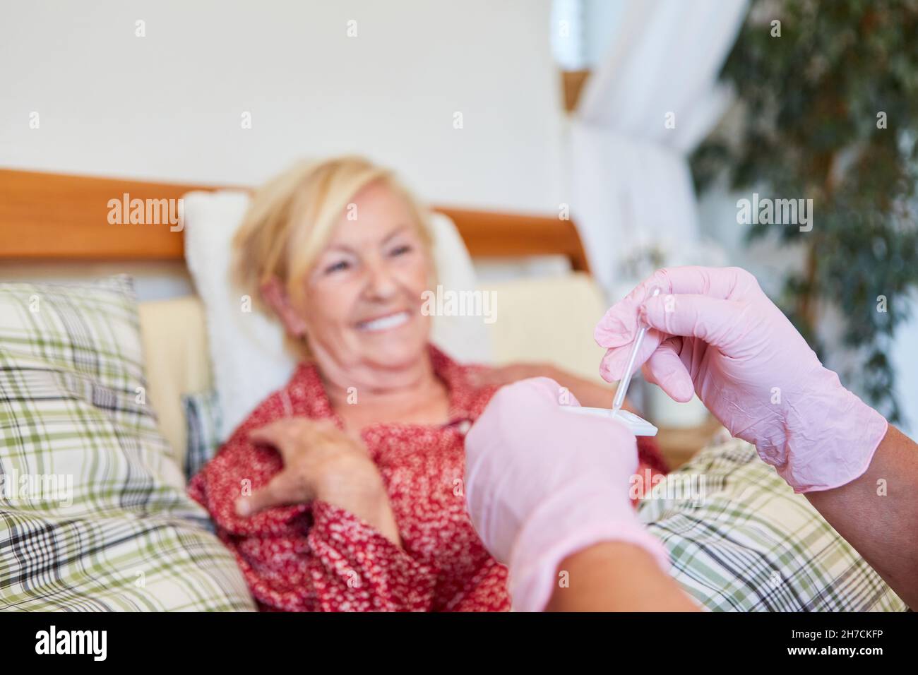 Die Krankenschwester führt einen CRP-Schnelltest für eine Blutzählungsanalyse im Seniorenheim durch Stockfoto