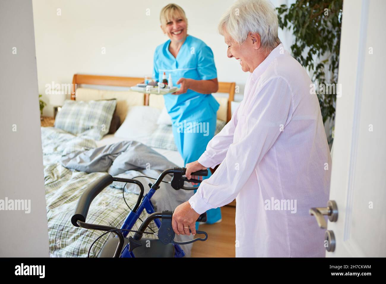 Ältere Patientin mit Rollator in der Reha-Klinik und Krankenschwester mit Medikamenten Stockfoto