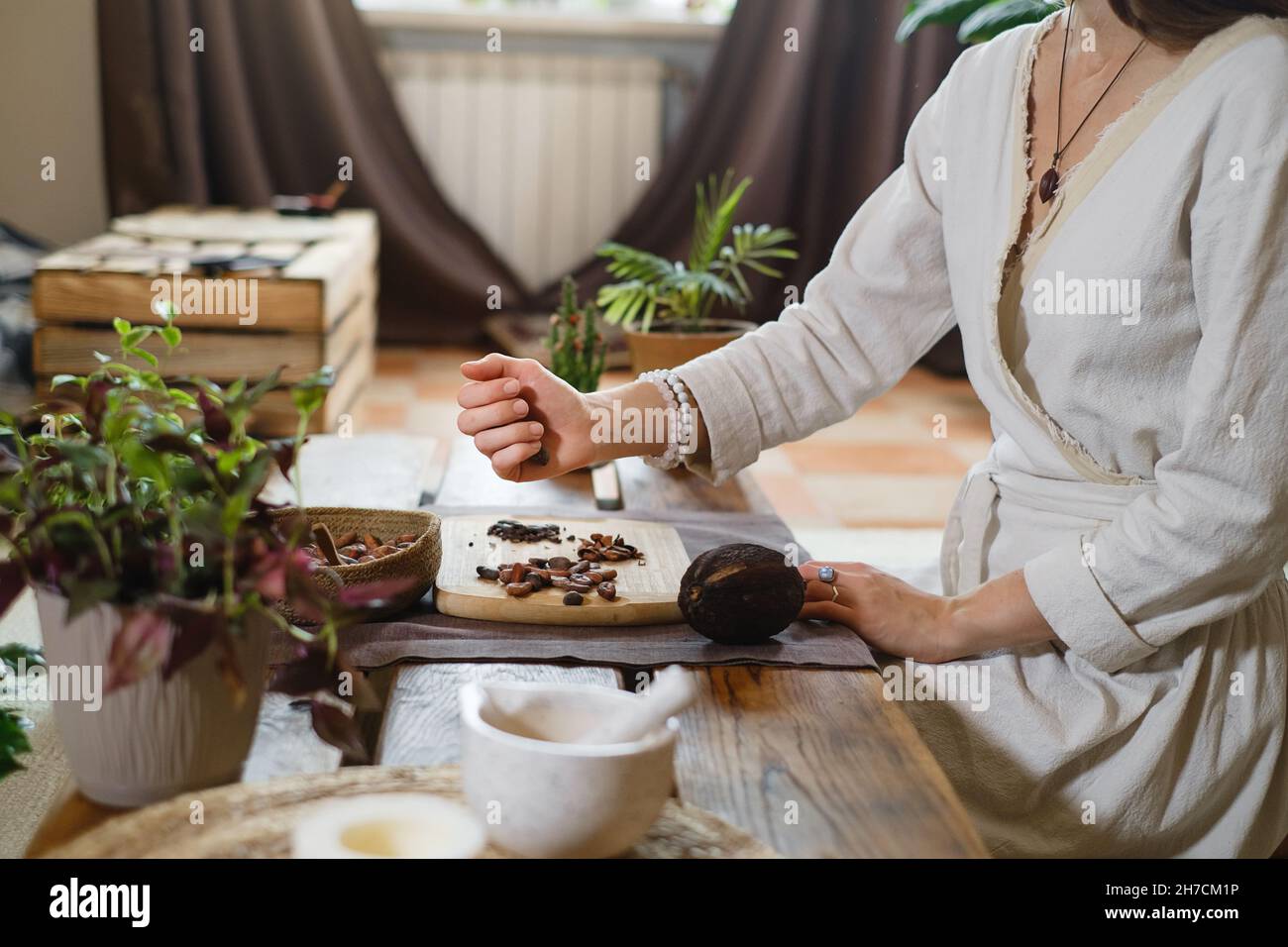 Heißer handgemachter zeremonieller Kakao in Tasse. Frau Hände halten hausgemachten Kakao, Draufsicht auf Holztisch. Bio gesundes Schokoladengetränk, zubereitet aus Stockfoto