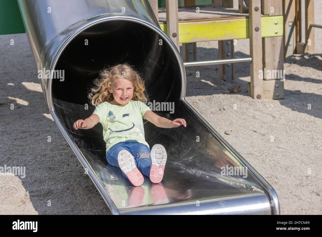 Kleines Mädchen mit fröhlichen Lachen und fliegenden Haaren auf Rutsche, Deutschland, Bayern Stockfoto