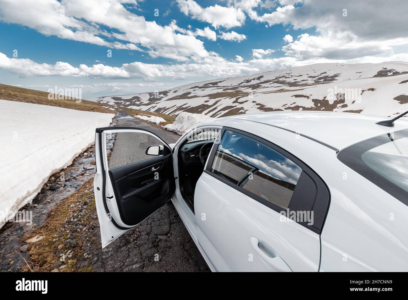 Eine schmale und gefährliche Asphaltstraße windet sich im Winter hoch in den Bergen. Hohe Schneeverwehungen blieben auf der Seite der Autobahn Stockfoto