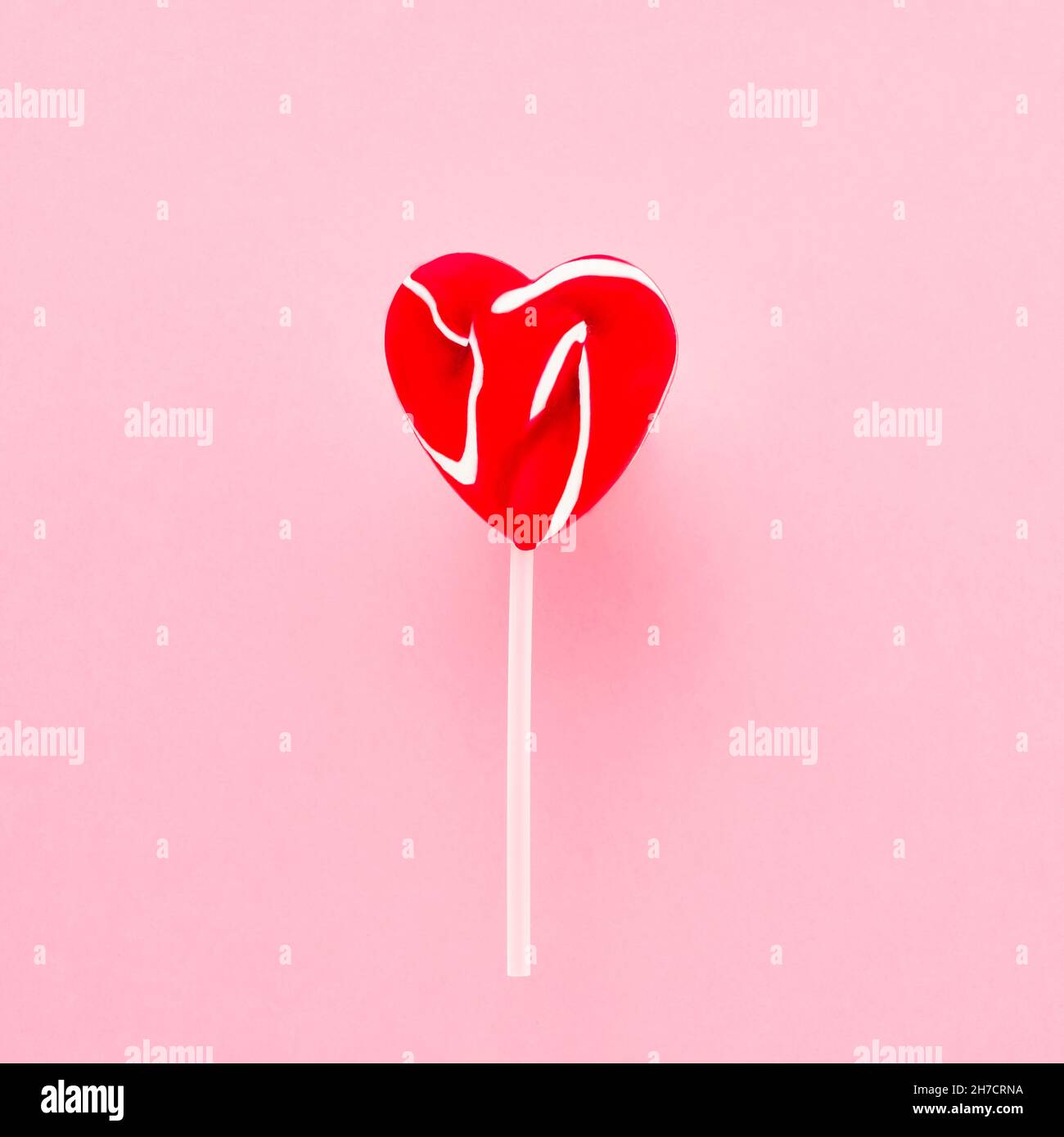 Rotes Lollipop-Herz auf weißem Stock auf rosa Hintergrund. Draufsicht, Platz für Text kopieren Stockfoto