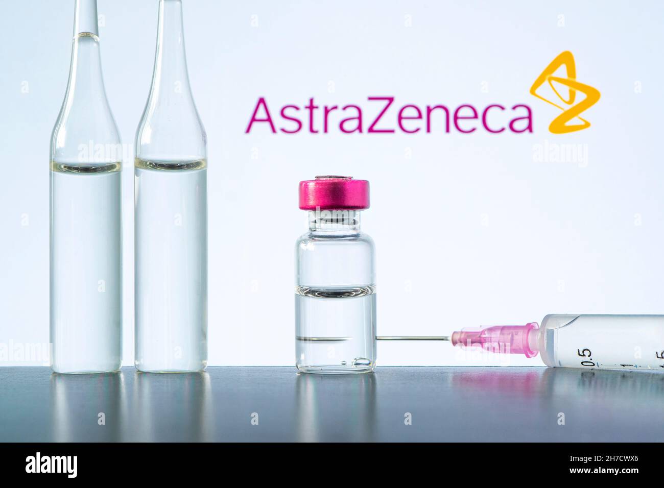 Eine Impfspritze und eine Glasampulle mit einer klaren Flüssigkeit auf blauem Hintergrund mit dem Logo eines Pharmaunternehmens astrazeneca. 15. März 20 Stockfoto