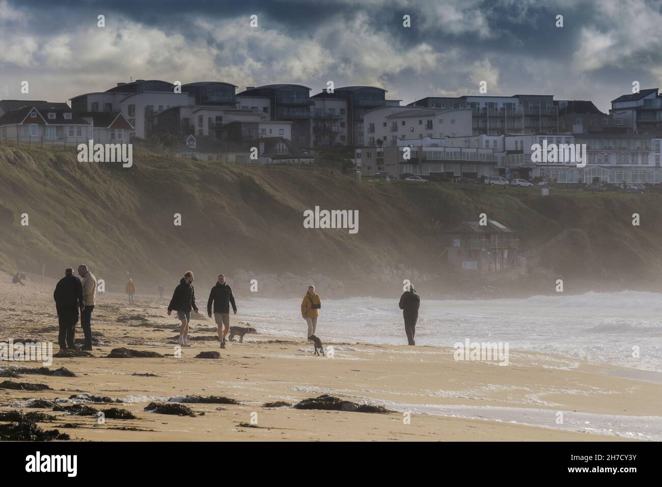 Bei windigem Wetter genießen die Menschen einen flotten Spaziergang am Strand im Fistral in Newquay in Cornwall. Stockfoto