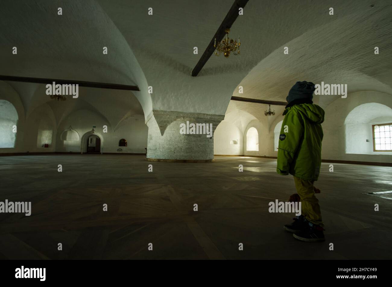 Ein Junge in der Mitte einer riesigen Halle. Monastische Refektoriumskammer auf Solowki. Russland, Region Archangelsk Stockfoto