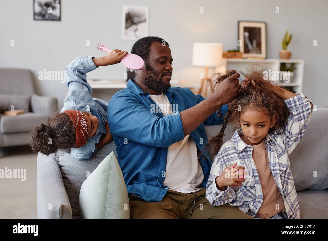 Porträt eines afroamerikanischen alleinerziehenden Vaters, der sich zwei niedliche Mädchen zu Hause die Haare putzt, Kopierraum Stockfoto