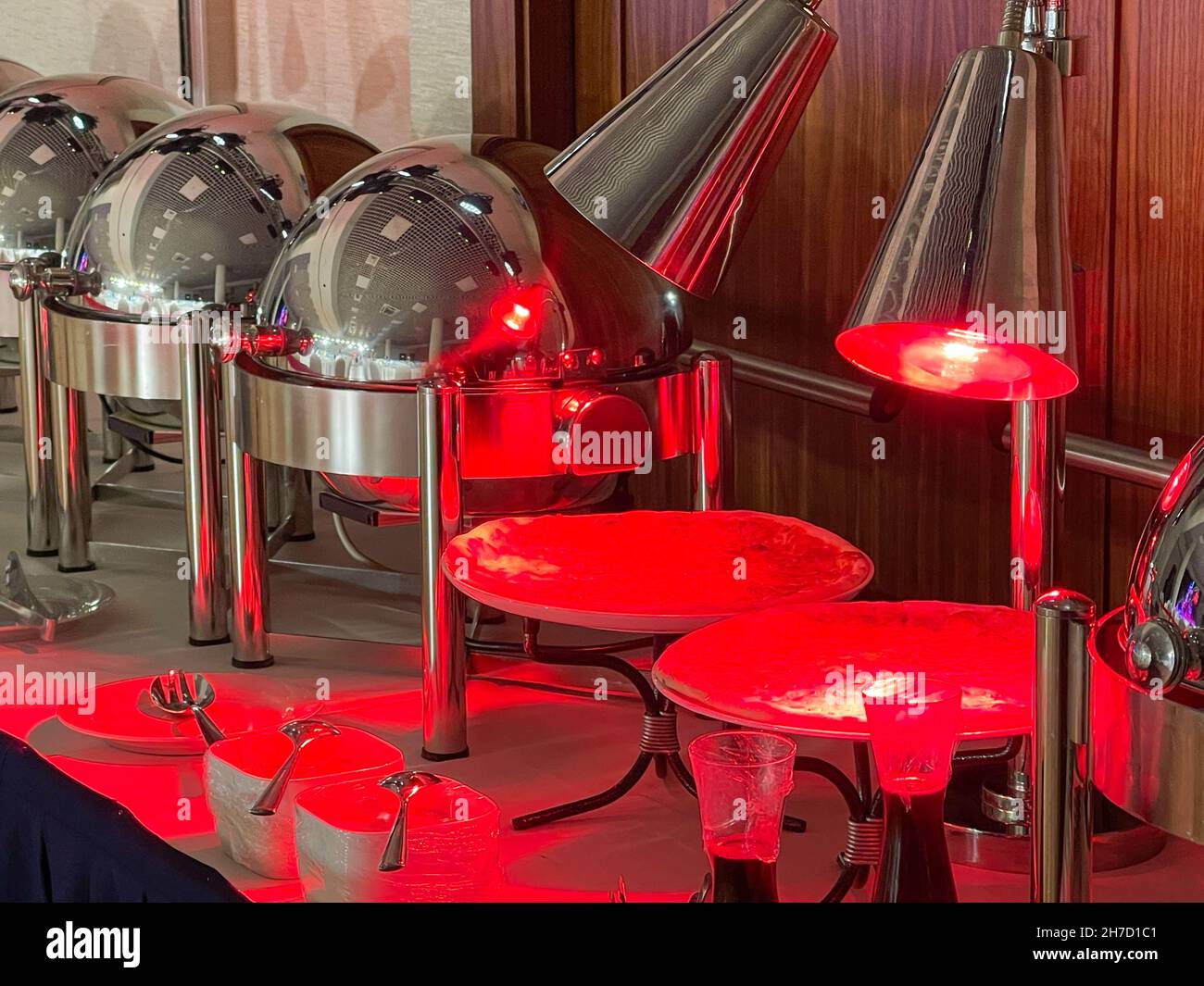 Tisch mit leuchtenden Lampen und Behältern für Bankette im Restaurant Stockfoto
