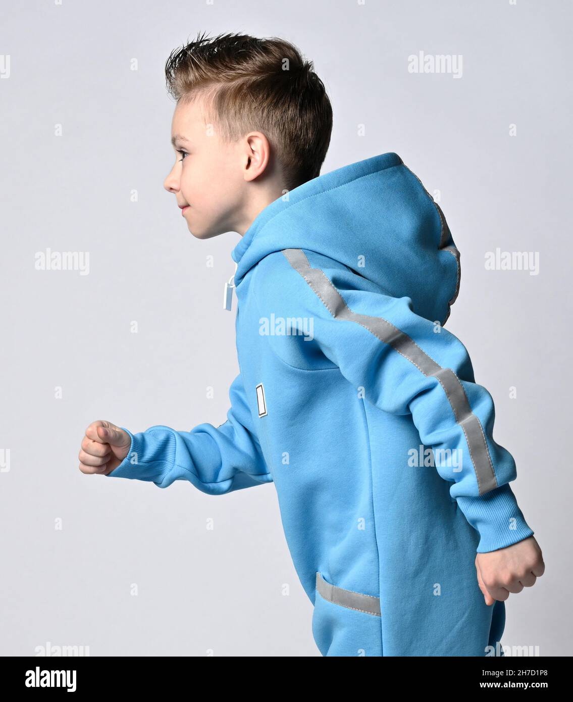 Porträt eines frolic, aktiven Jungen in blauen Jumpsuit mit Kapuze und  Taschen mit reflektierenden Streifen laufen. Seitenansicht Stockfotografie  - Alamy