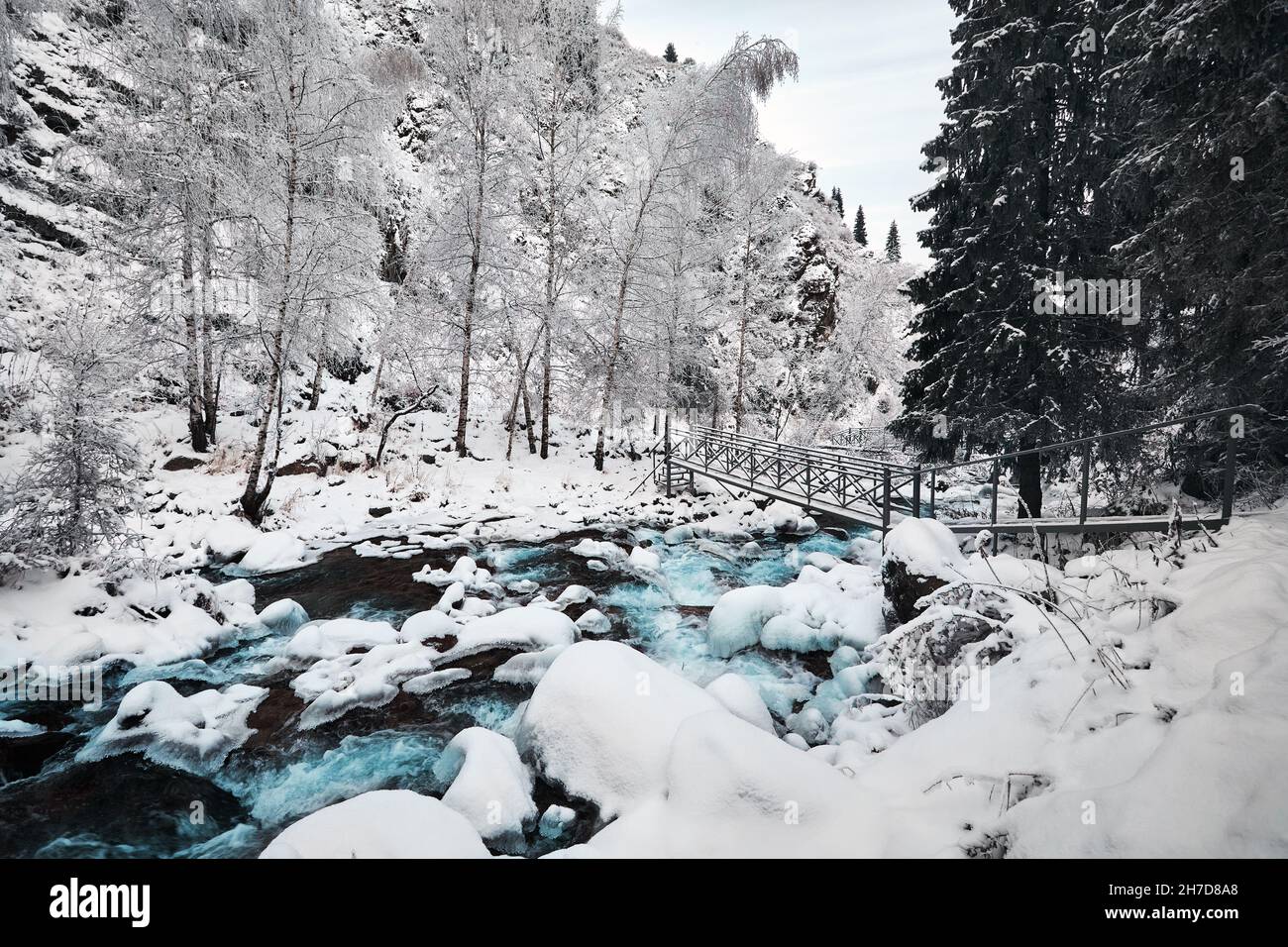 Schöne Landschaft von blauem Wasser Fluss und Fichte Baumwald In den Bergen mit Schnee im Winter Stockfoto