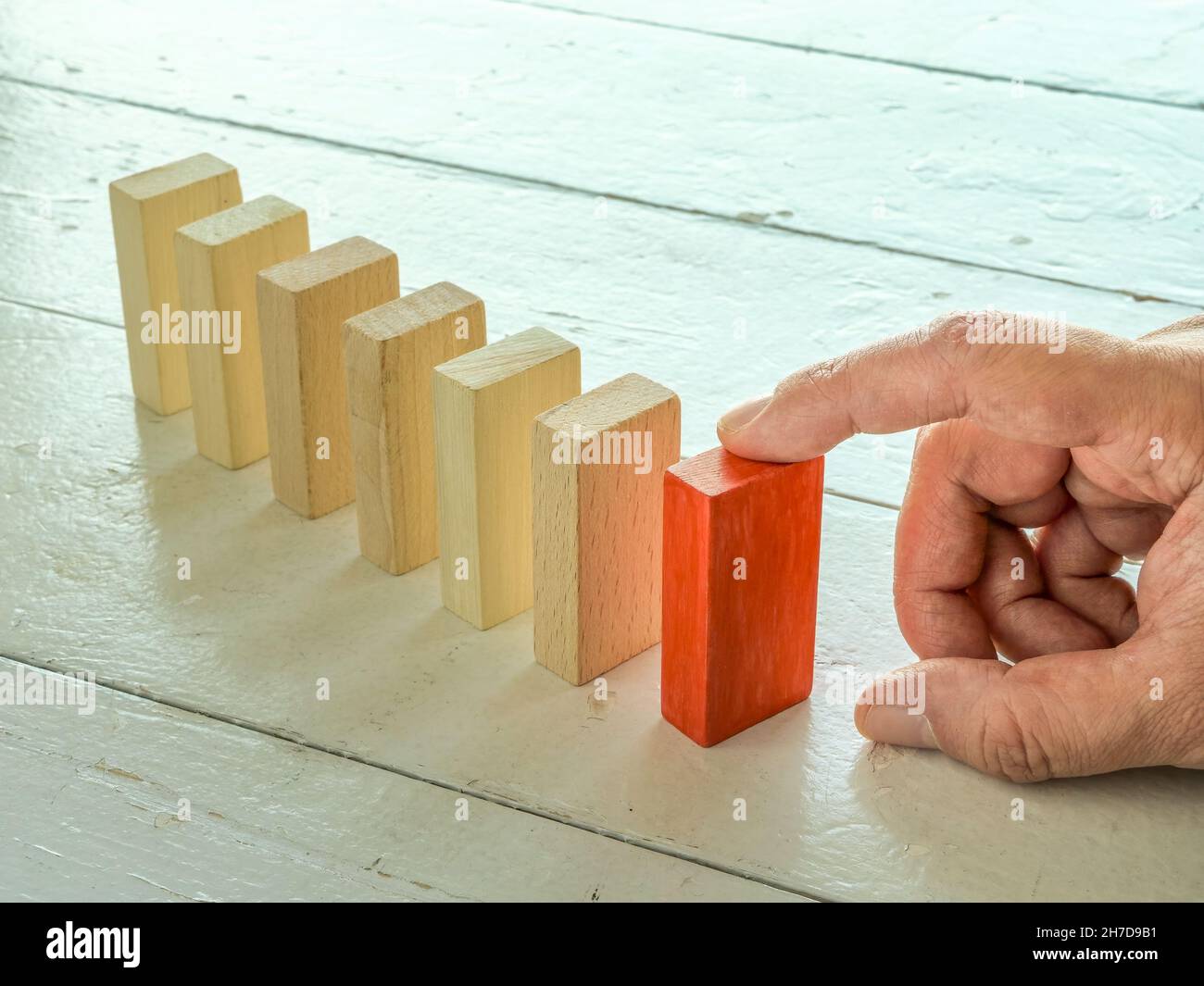 Konzept zur Ursachenanalyse. Der Finger hält die erste Kachel in der Domino-Linie. Stockfoto