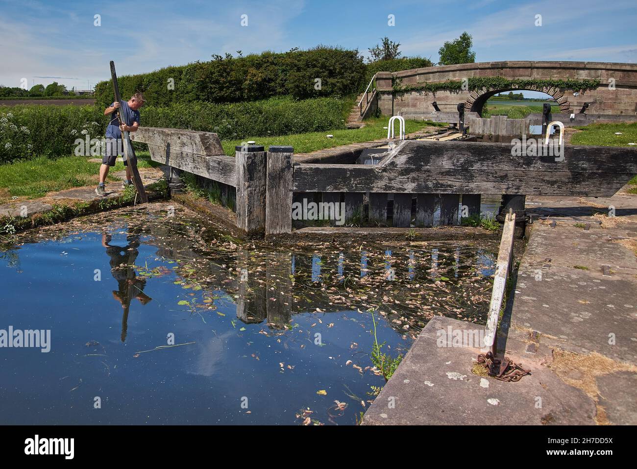 Ein Mann, der an einer altmodischen traditionellen Schleuse auf der abgelegenen ländlichen Rufford-Filiale der Kanäle Leeds und Liverpool im Nordwesten Englands arbeitet Stockfoto