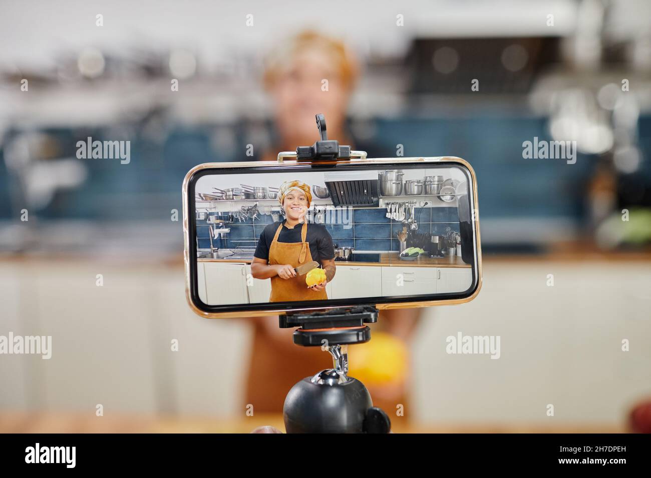 Porträt einer lächelnden Köchin auf dem Smartphone-Bildschirm, die Videos aufzeichnet oder in der Küche Live-Stream macht, Platz zum Kopieren Stockfoto