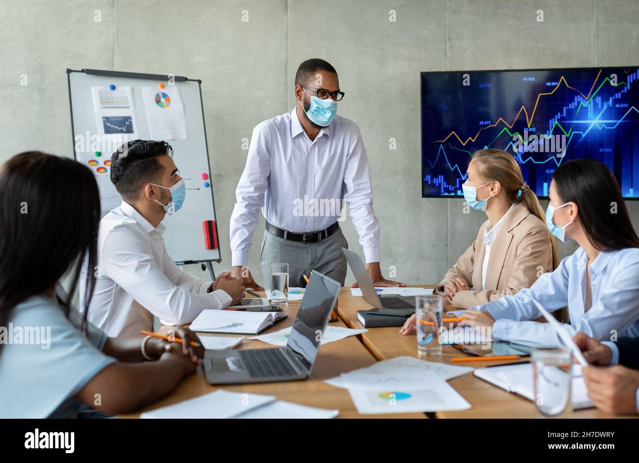 Firmenmeeting. Schwarzer Boss Trägt Gesichtsmaske Mit Geschäftskonferenz Mit Kollagen Stockfoto