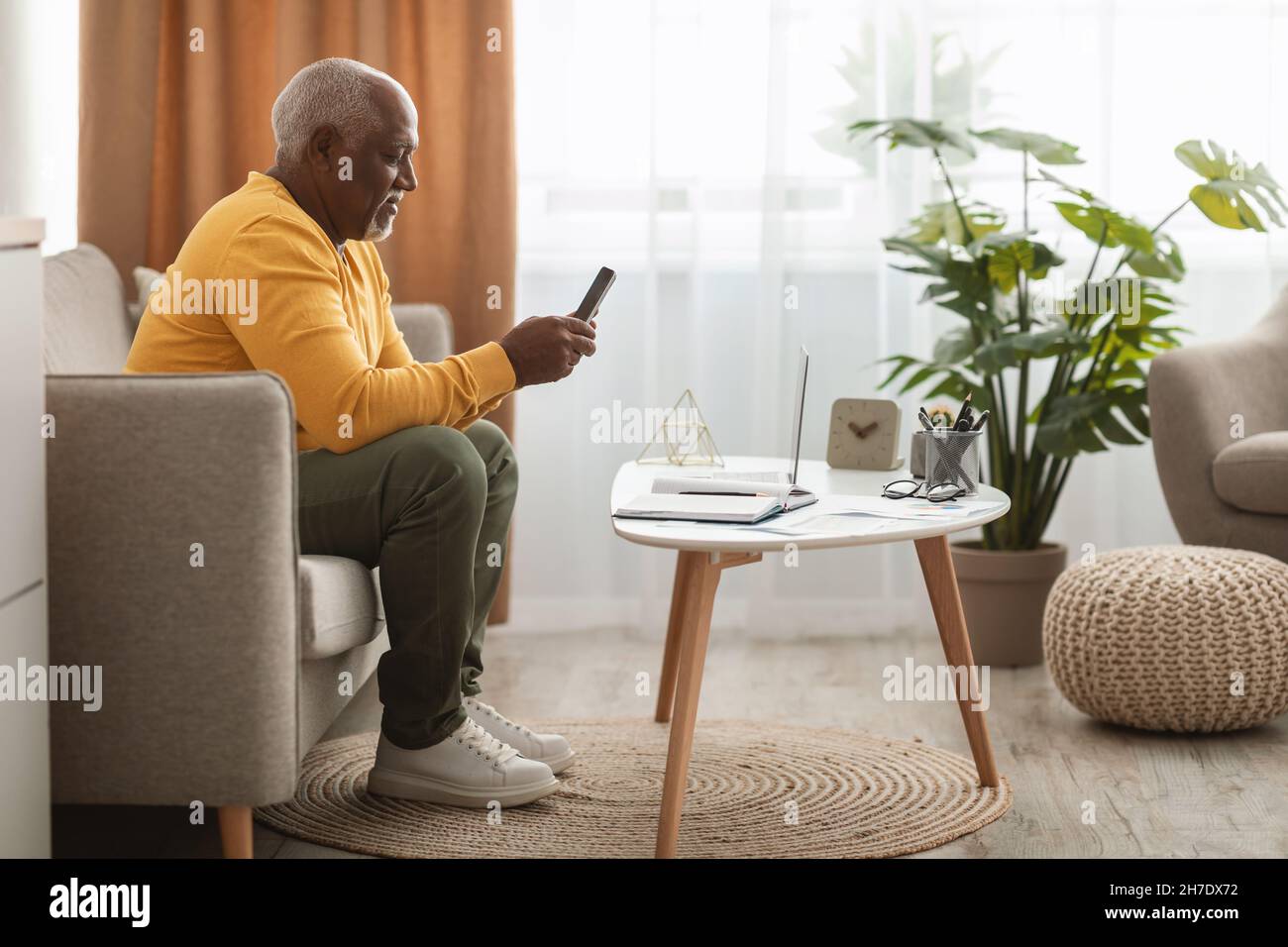 Reifen Schwarzen Mann Mit Smartphone Texting Sitzen Auf Laptop Indoor Stockfoto