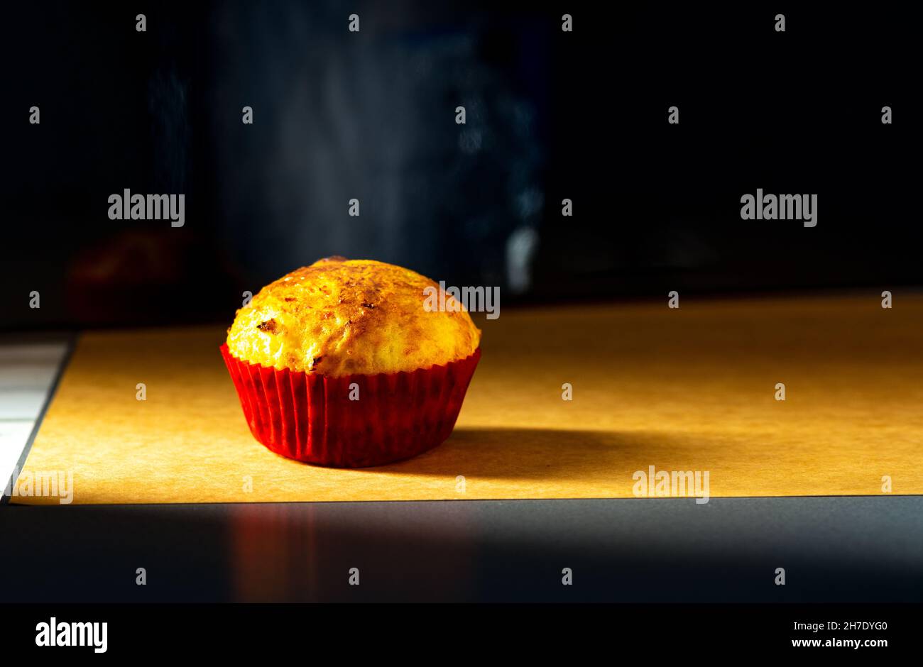Ein Cupcake wird mit Seitenlicht im Studio auf einem alten Papierhintergrund geschossen. Wohnküche Stockfoto