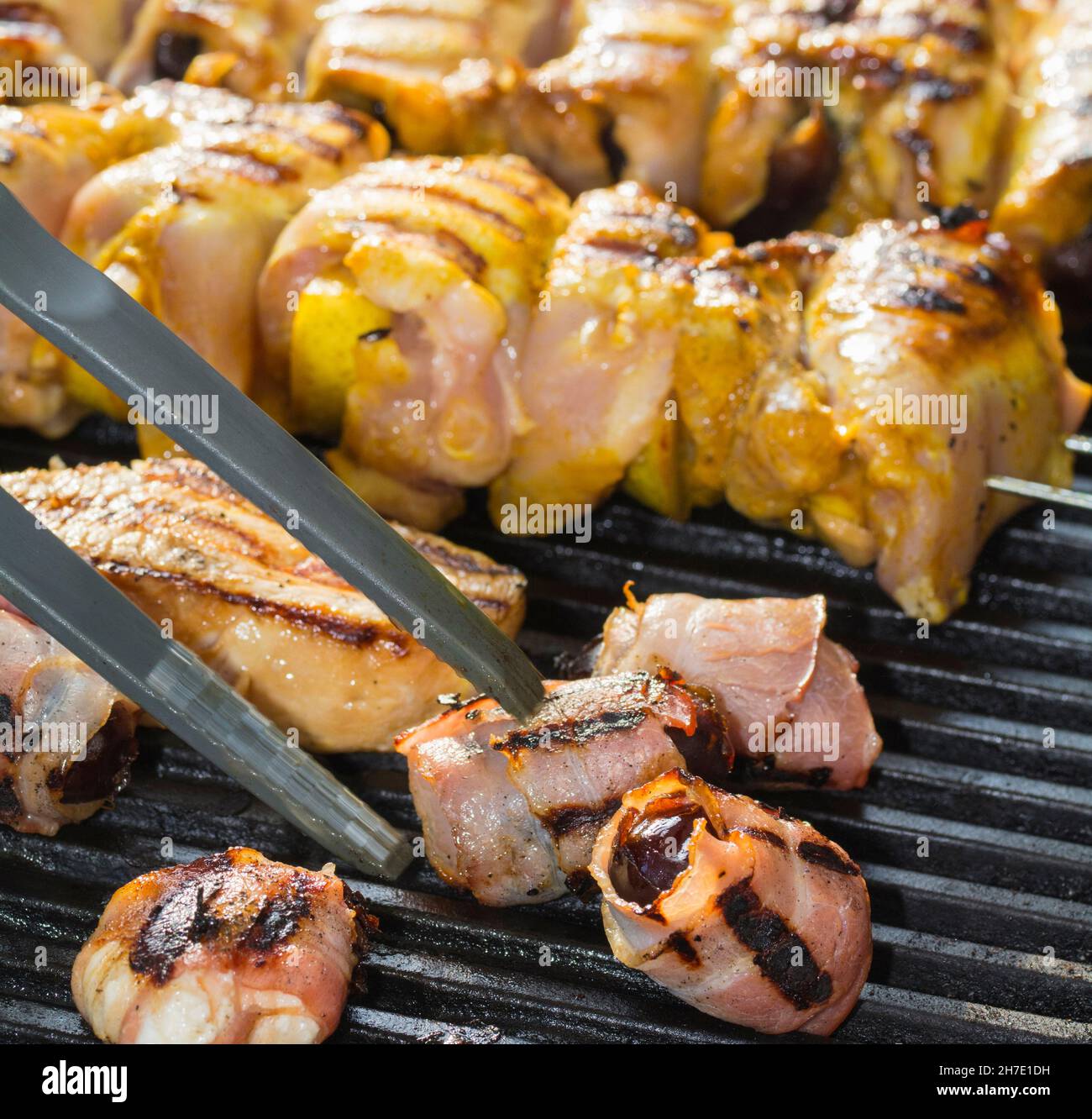 Datteln in Speck und Fleischkebabs auf einem Grill Stockfoto
