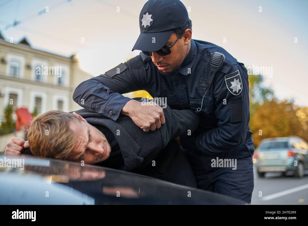 Polizeibeamter in Sonnenbrillen verhaftet jungen Mann Stockfoto