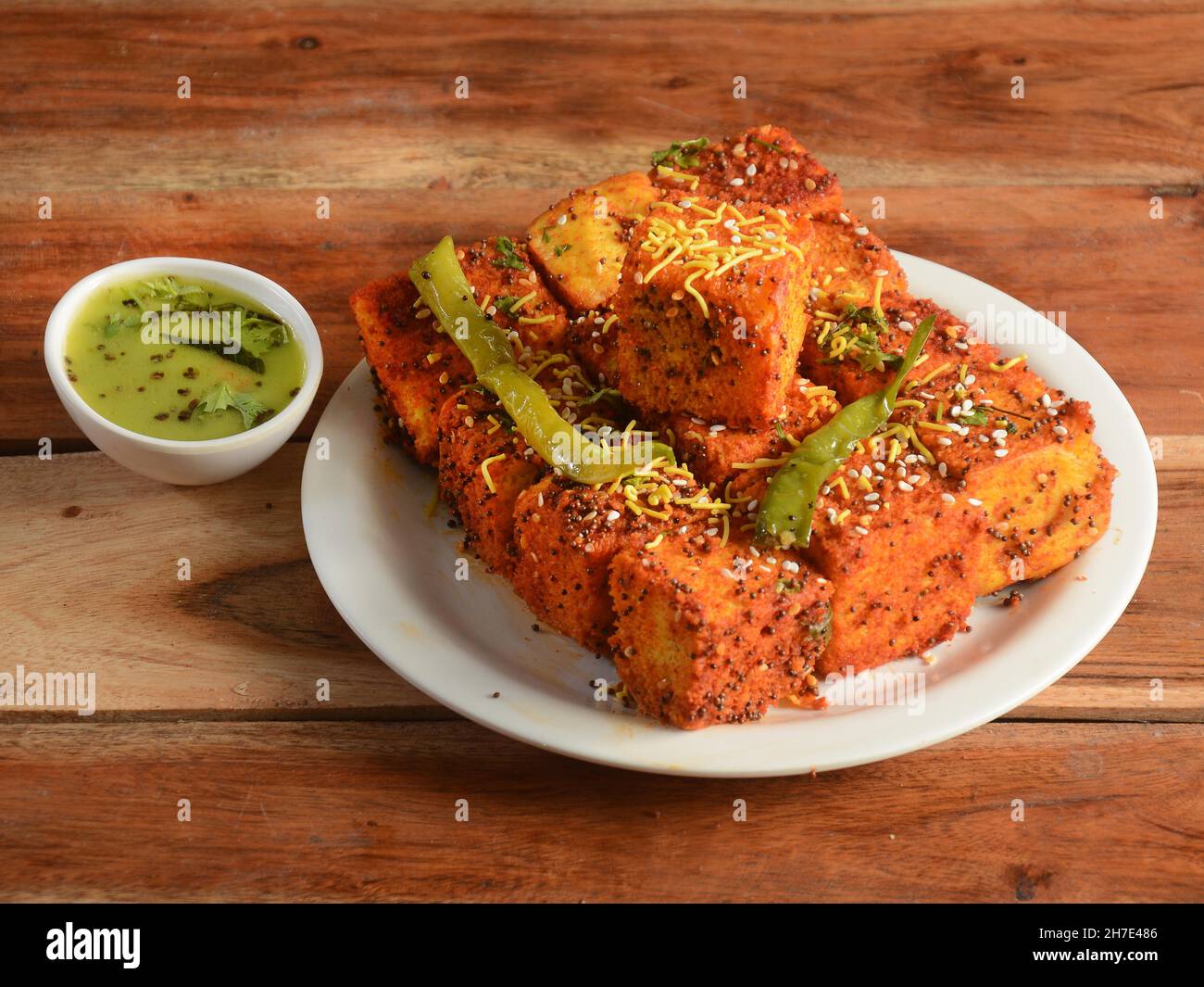 Masala Dhokla aus Reis oder Urad dal ist ein beliebtes Frühstück oder Snacks Rezept aus Gujarat, Indien, serviert mit Green Chutney und gebratenen Chili. Se Stockfoto