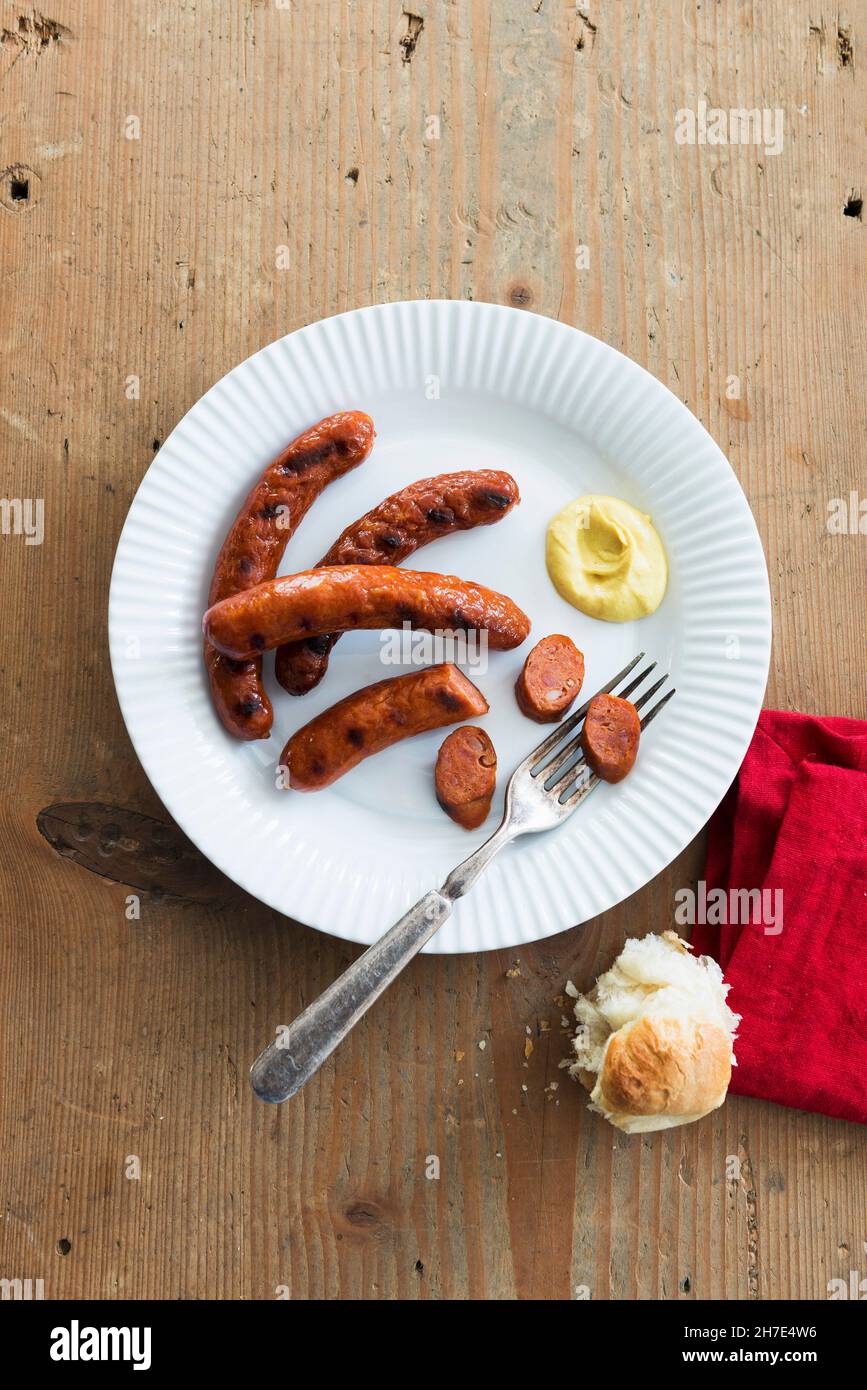 Gegrillte Merguez-Würste mit Senf und einer Rolle Stockfoto