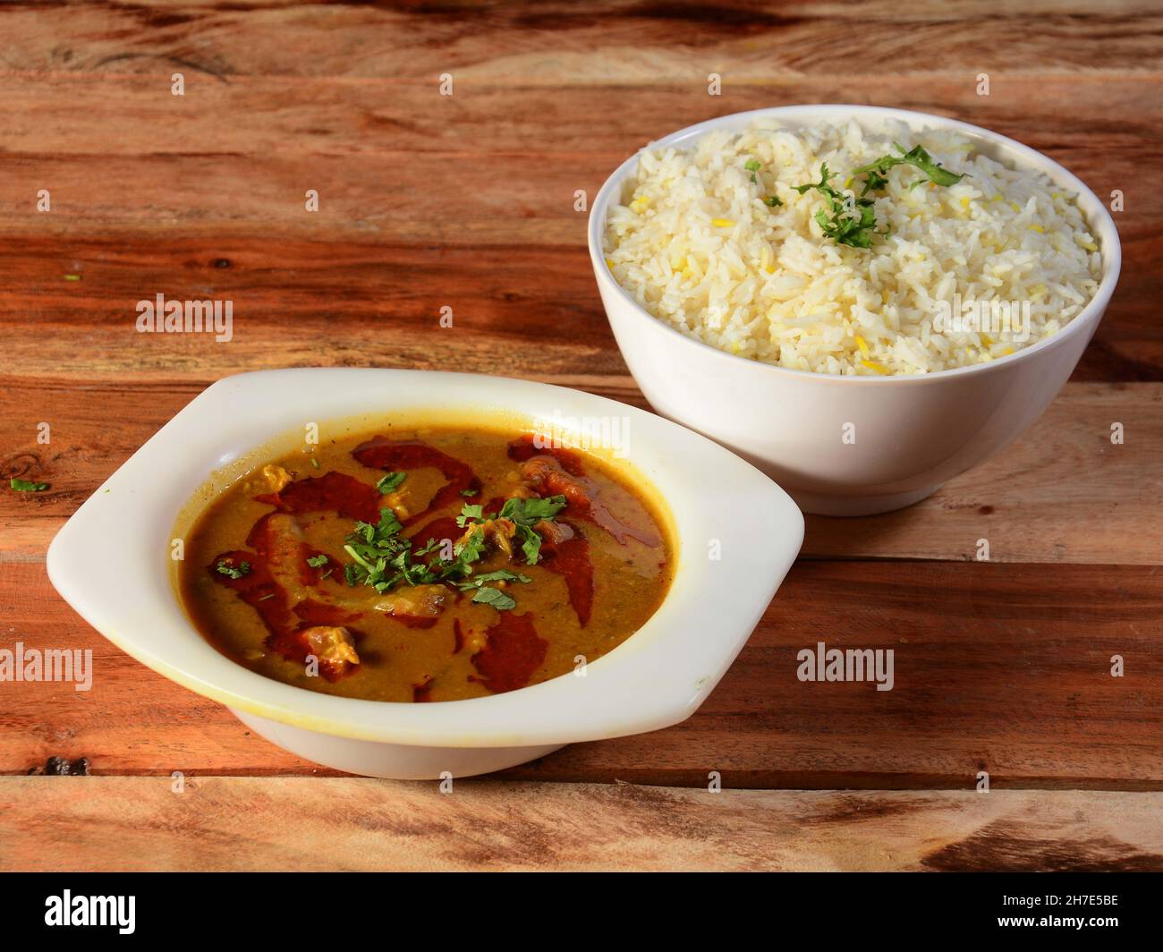 Traditionelle indische Küche, Rindfleisch-Cuisine und gekochter Reis auf weißer Keramikschale auf rustikalem Holzhintergrund Stockfoto