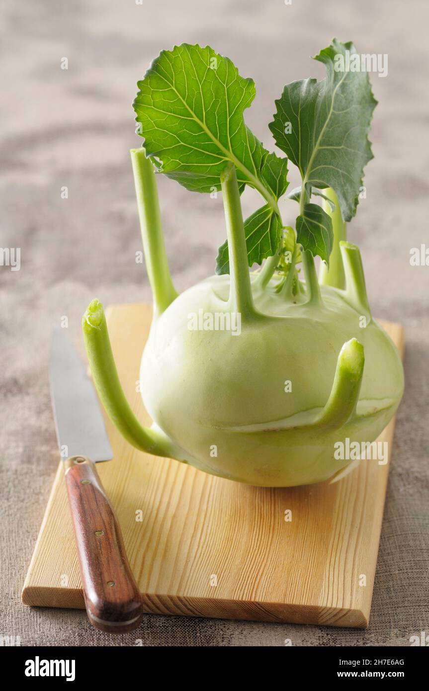 Ein Kohlrabi mit Blättern auf einem hölzernen Brett Stockfoto