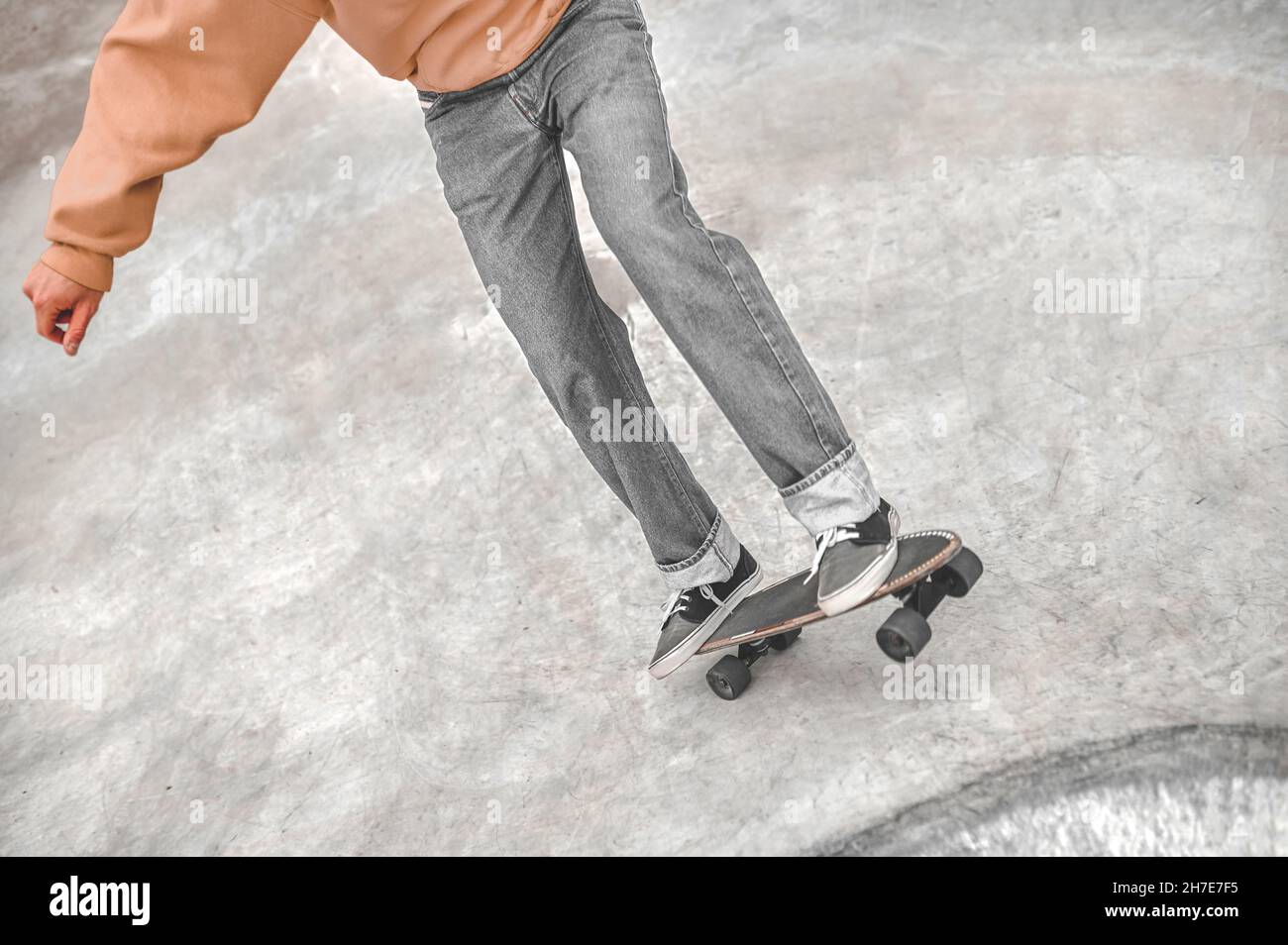Beine von Kerl, der auf Skateboard auf glatter Oberfläche rutscht Stockfoto