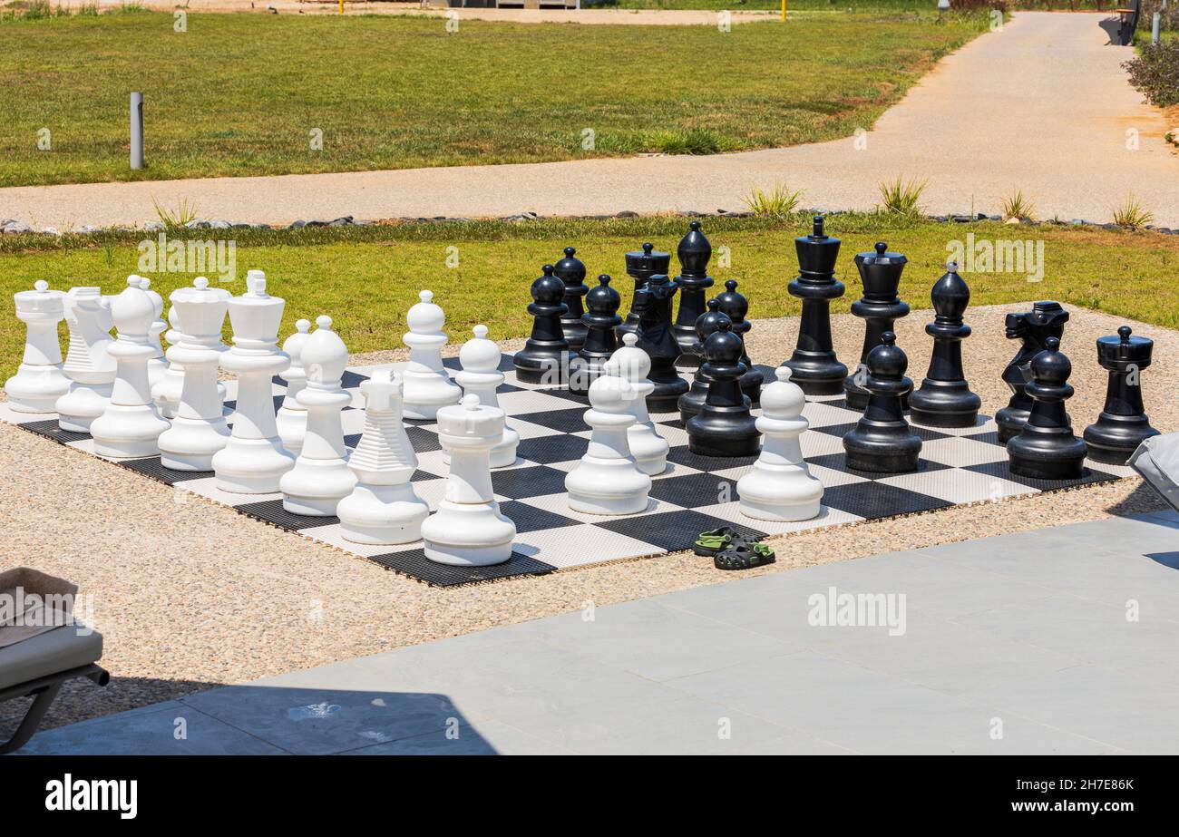 Schachbrett mit riesigen schwarz-weißen Schachfiguren für Freiluftspiele am Strand. Griechenland. Stockfoto