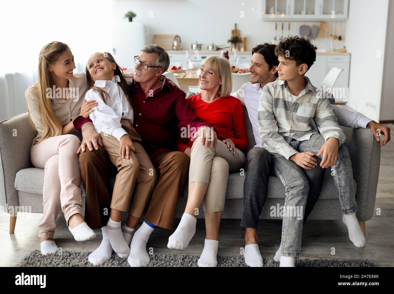 Eine große Familie mit mehreren Generationen, in der sich die Kinder auf dem Sofa entspannen, lächeln und plaudern, um zu Hause die Zeit miteinander zu verbringen Stockfoto