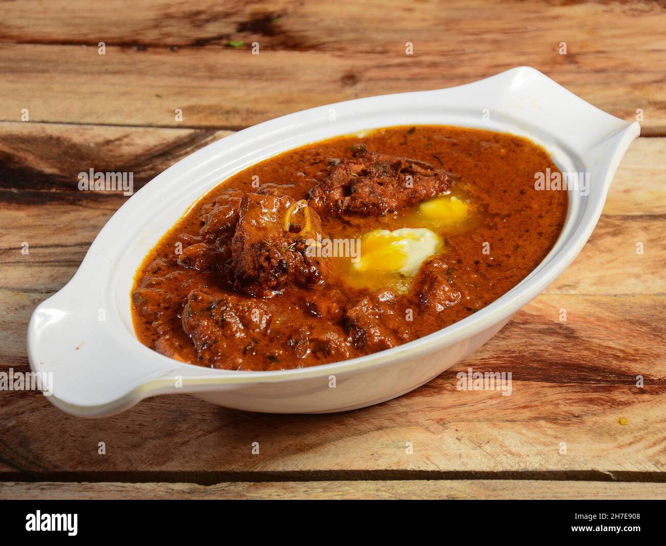 Indisches Butter-Huhn oder Murgh Makhani in einer Schüssel über einem rustikalen Holzhintergrund. Selektiver Fokus Stockfoto