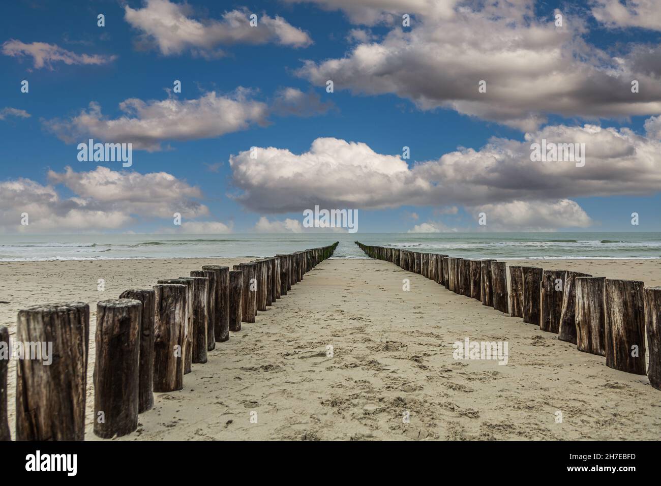 Sandstrand bei Burgh-Haamstede in der niederländischen Provinz Zeeland mit einer doppelten Reihe von Strandpfosten im Meer, die als funktioneller Küstenschutz vorgesehen sind Stockfoto