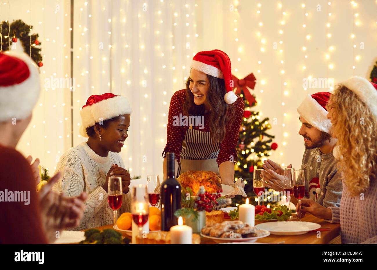 Fröhliche multiethnische Freunde, die am Heiligabend essen Stockfoto