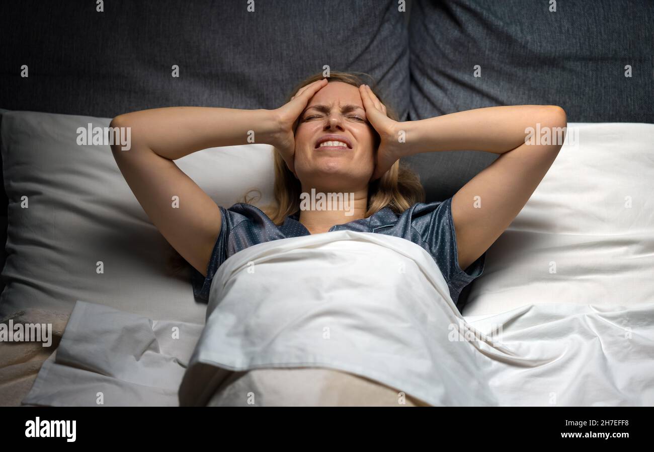 Frau mit Kopfschmerzen in der Nacht Stockfoto