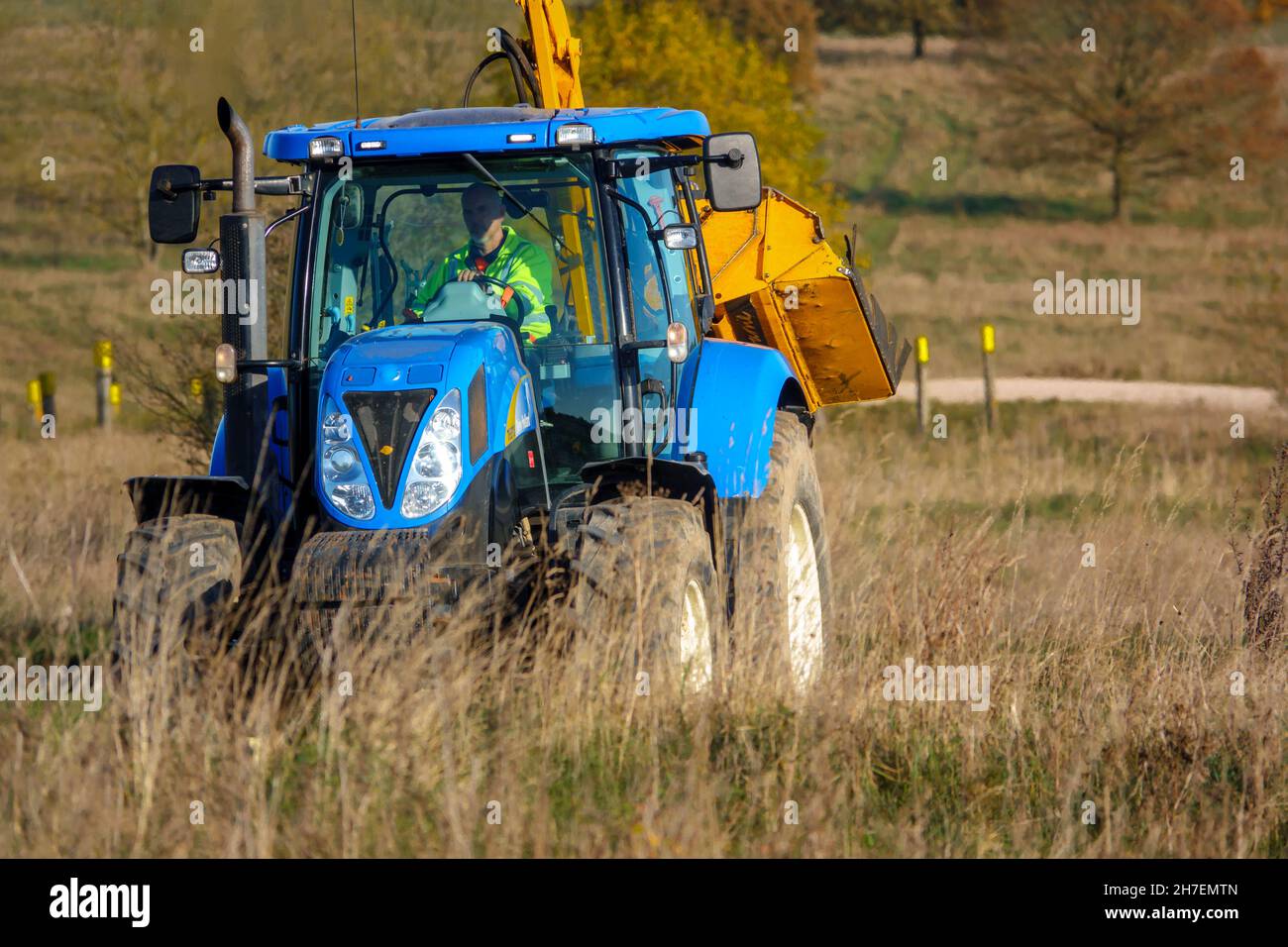 Großer blauer Traktor aus New Holland, ausgestattet mit Heckenschneidanlagen, ausgestattet für die Fahrt durch das Land, Wiltshire UK Stockfoto