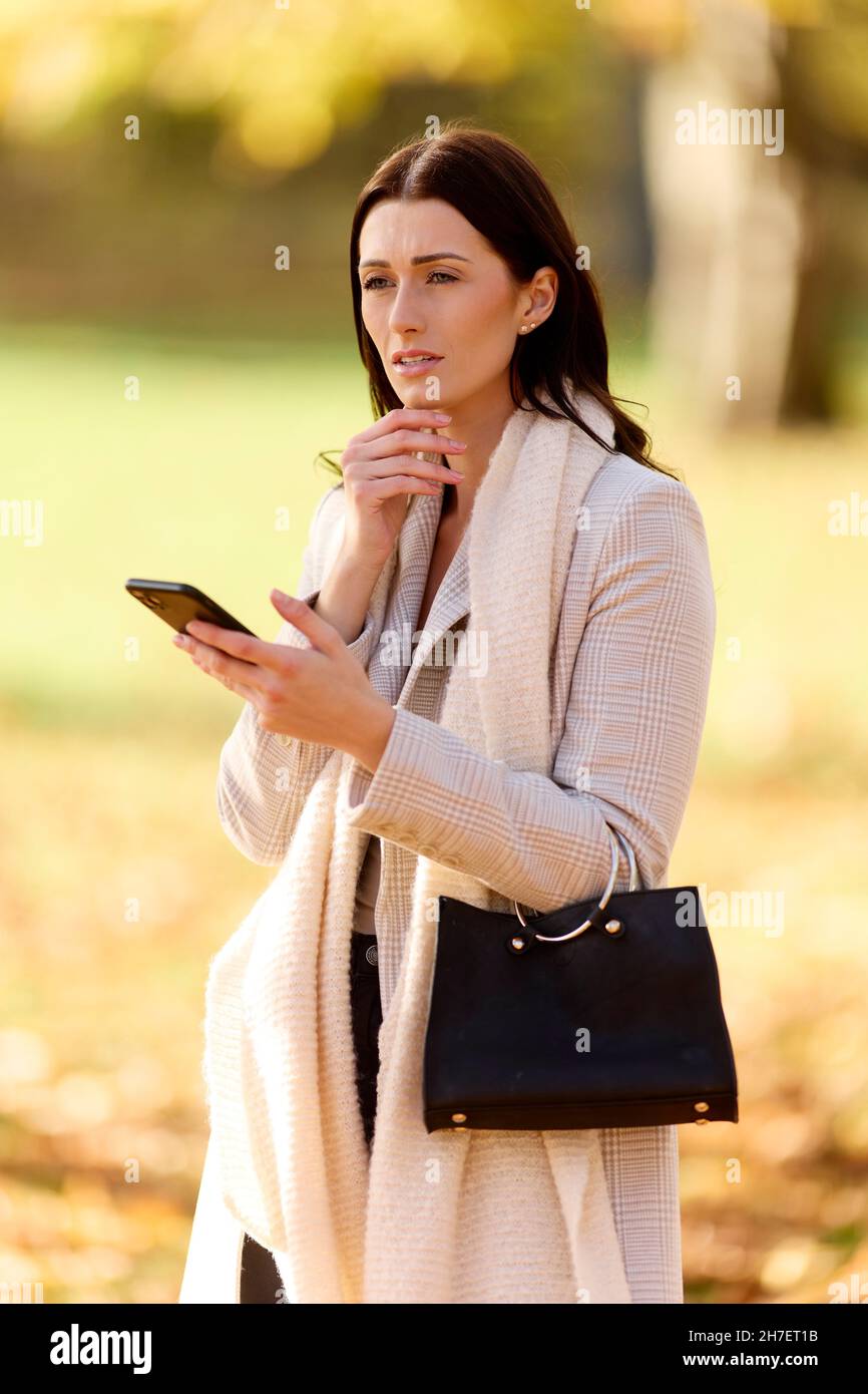 Besorgt aussehende Frau, die ihr Telefon anschaut Stockfoto