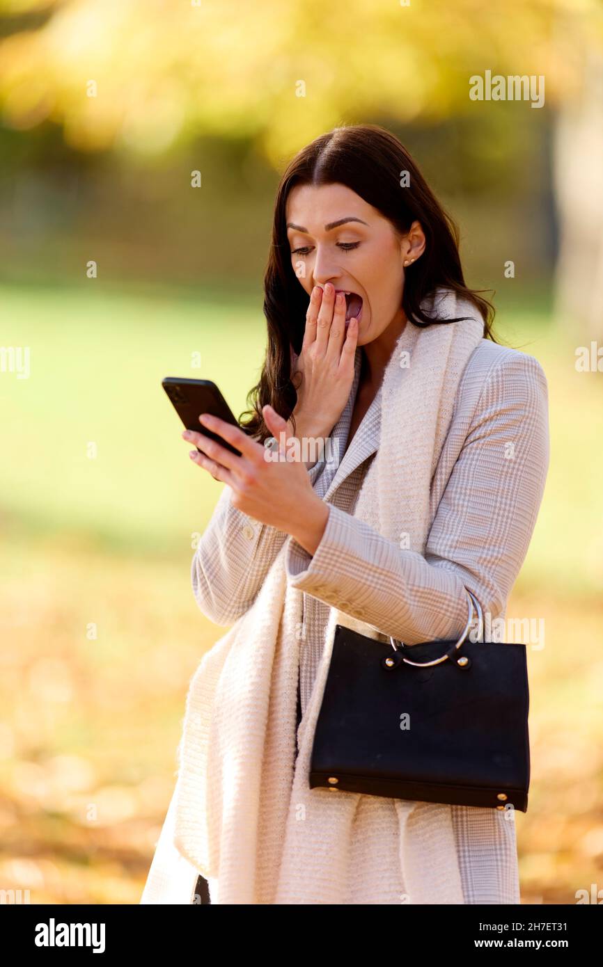 Frau suchen auf Ihr Telefon schockiert Stockfoto