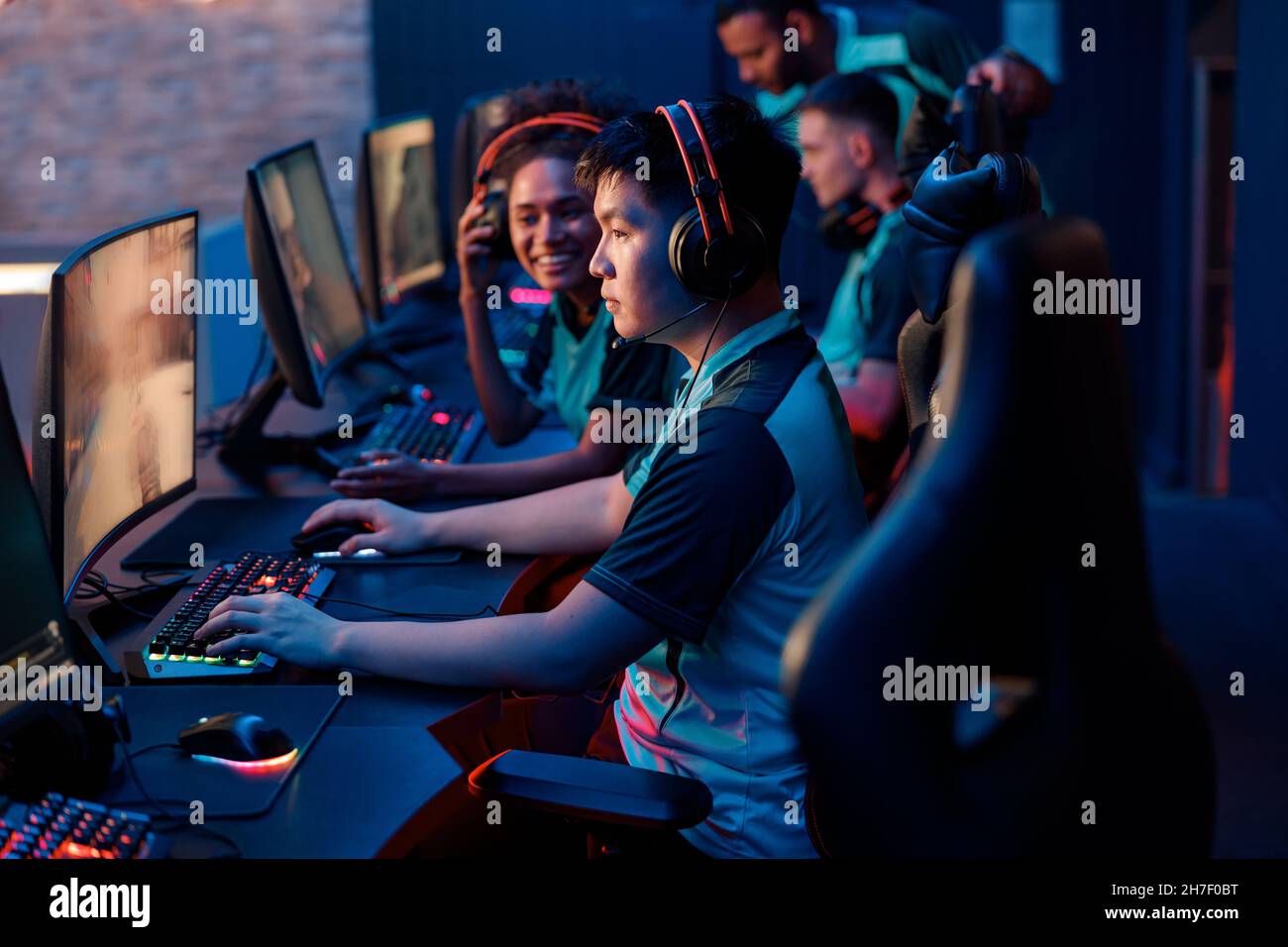Junge Spieler mit Headsets, die im Videospielclub spielen Stockfoto