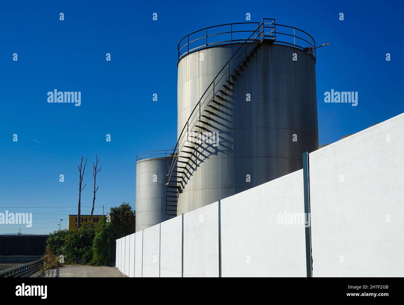 Große Lagertanks aus glänzendem Stahl mit Metallleitern Stockfoto