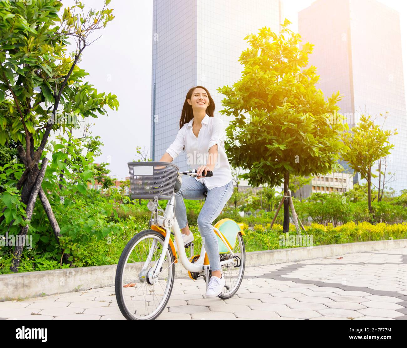 Junge attraktive Frau, die mit dem Fahrrad durch den Stadtpark fährt Stockfoto