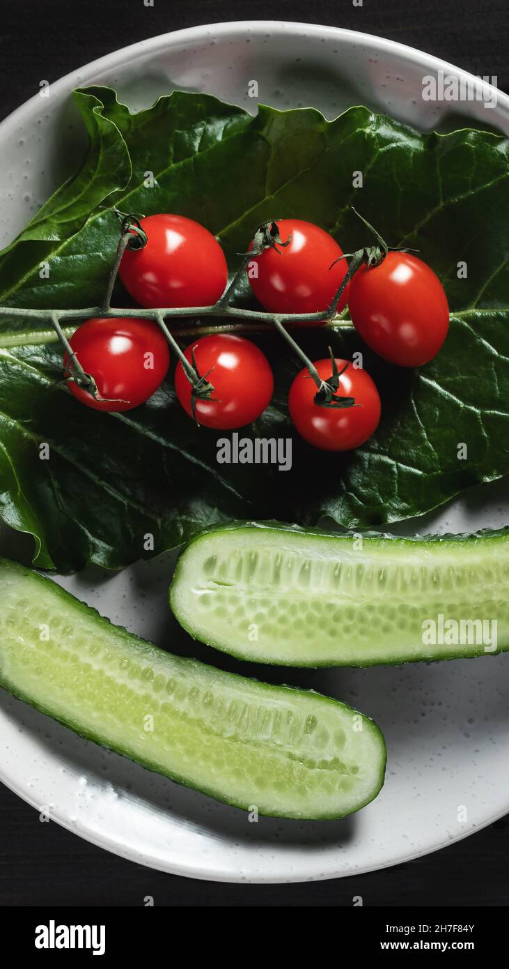 Frisches Gemüse und Kräuter auf einem Teller auf einem Holztisch. Konzept von Vegetarismus und gesunder Ernährung. Stockfoto