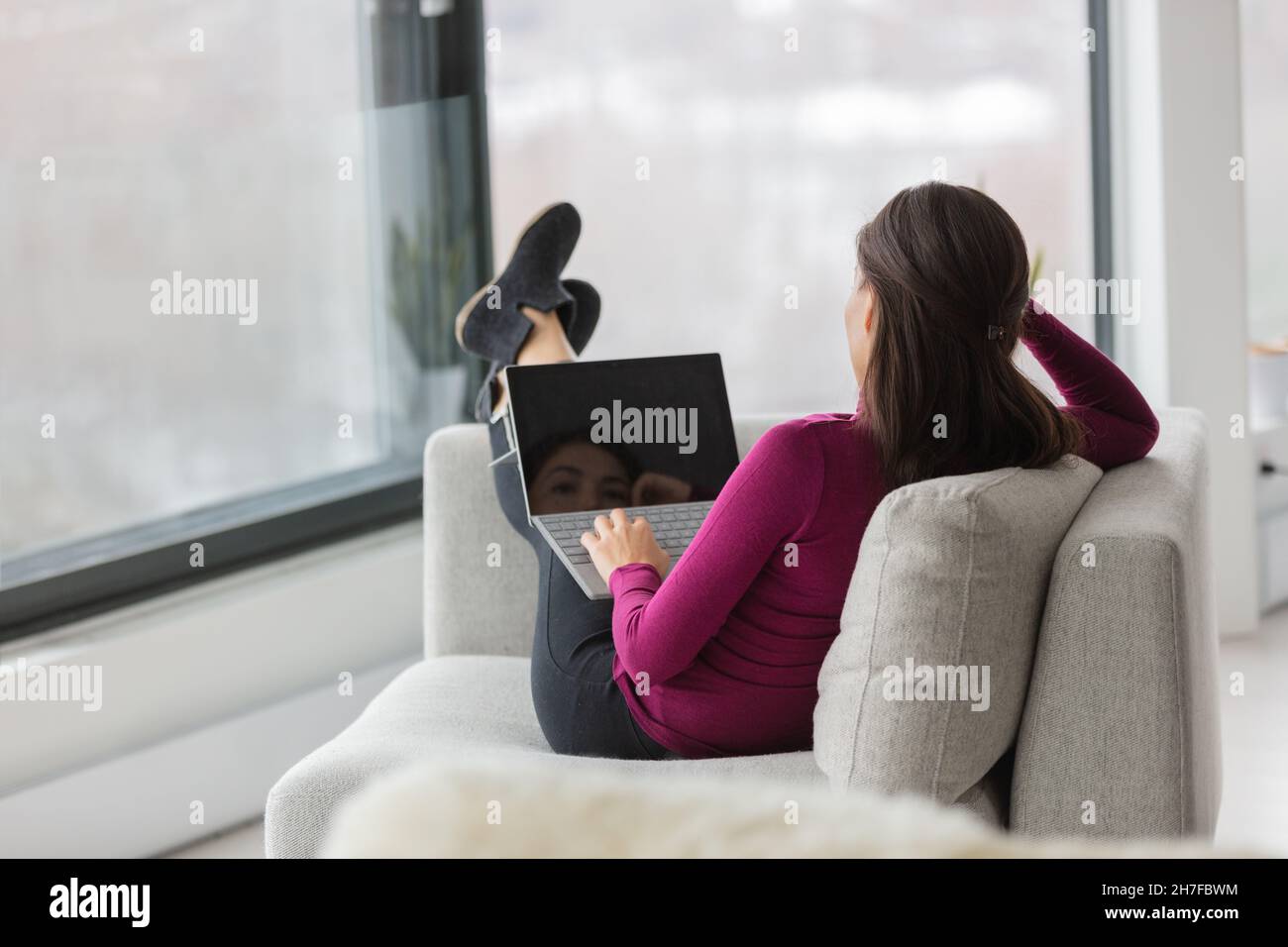Online-Schüler, die zu Hause studieren und Videoclips auf dem Laptop ansehen, sich auf dem Sofa im Wohnzimmer entspannen. Mädchen Füße oben entspannen in der Wohnung lässig Stockfoto