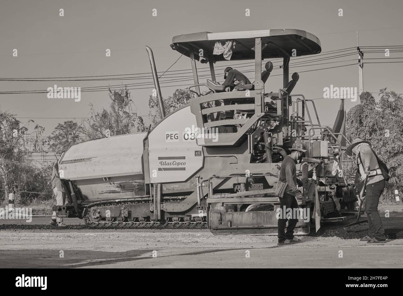 Phayao, Thailand - 27. Januar 2021: Schwarz-Weiß-Asphalt-Pflaster und Lastwagen und vier Arbeiter, die auf der Straße arbeiten Stockfoto