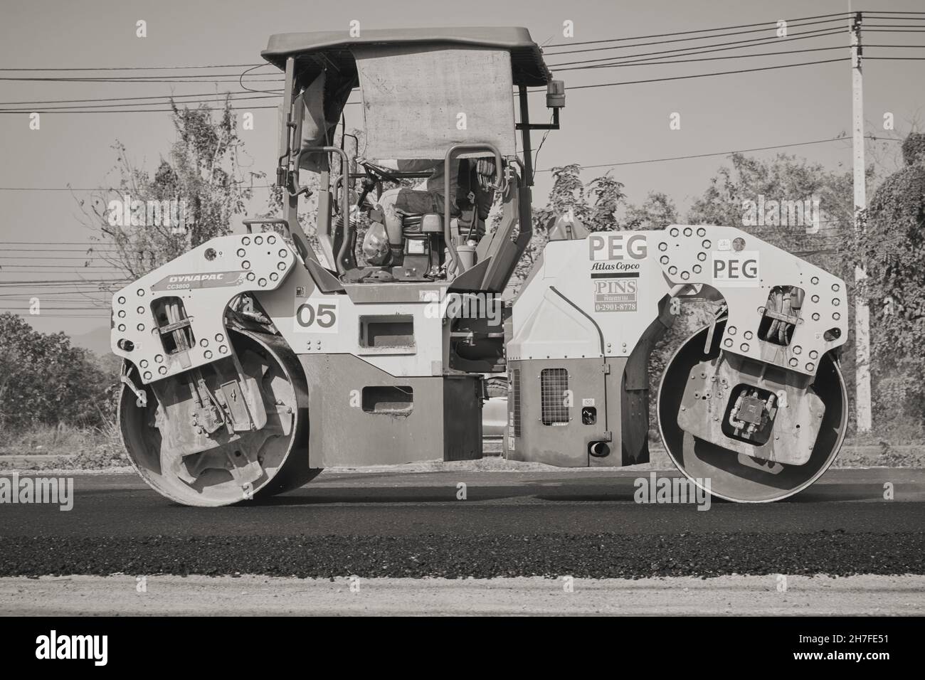 Phayao, Thailand - 27. Jan 2021: Zoom Side View Black and White Worker und Road Roller auf Asphalt Road Stockfoto