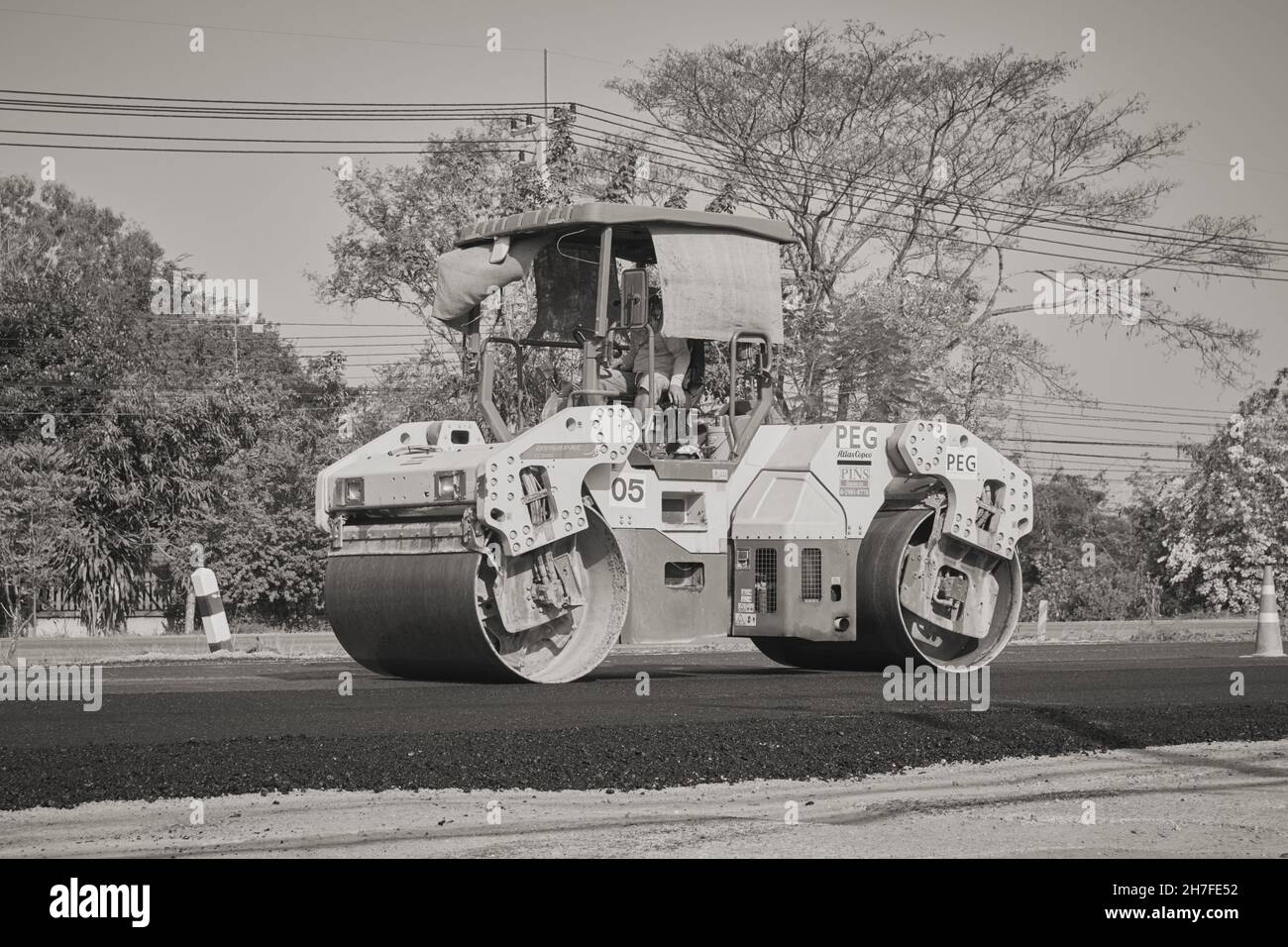 Phayao, Thailand - 27. Jan 2021: Vorne links Schwarz-Weiß-Arbeiter und Road Roller auf Asphalt Road Stockfoto