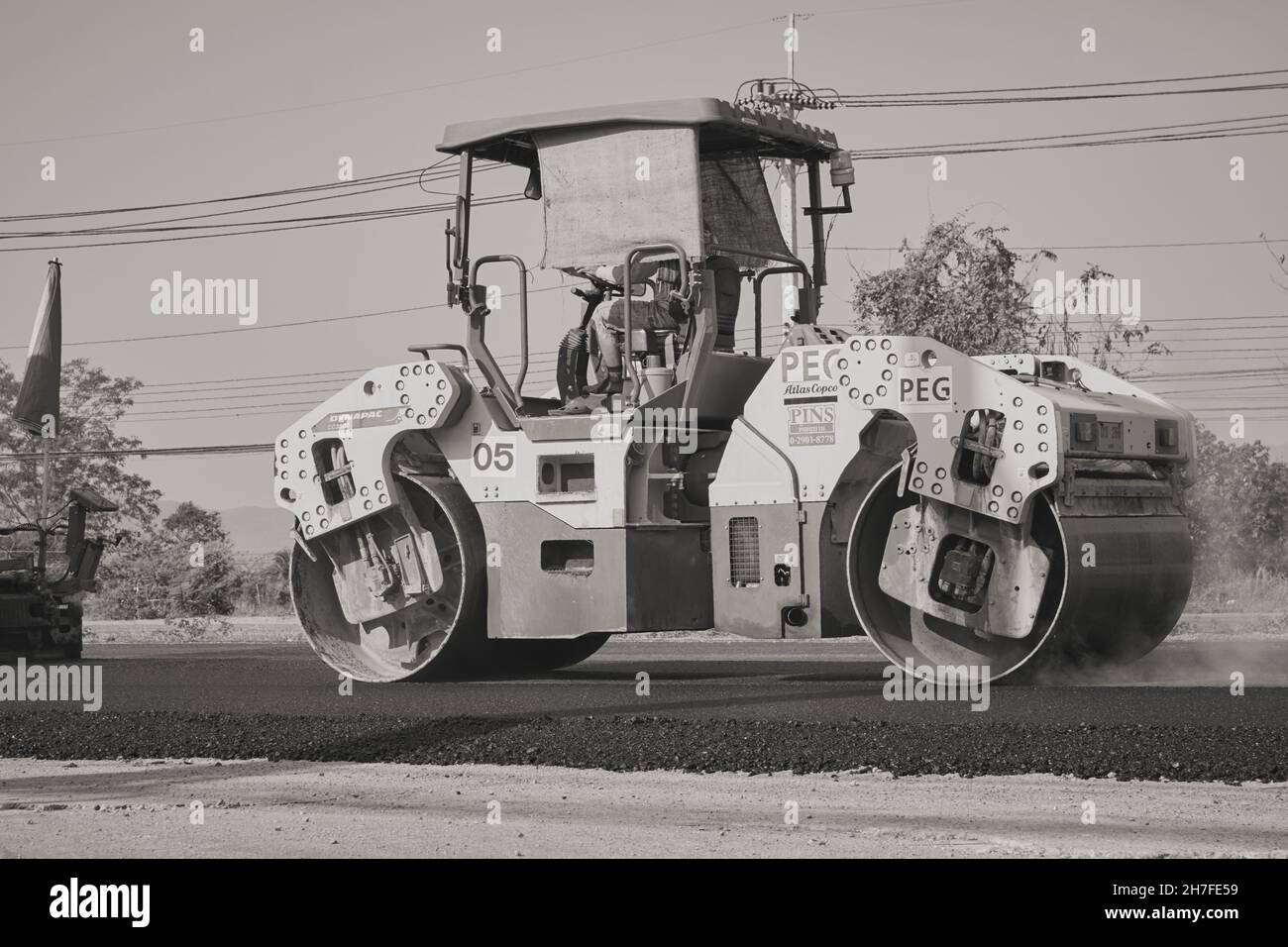 Phayao, Thailand - 27. Jan 2021: Zoom Back View Black and White Worker and Road Roller on Asphalt Road Stockfoto
