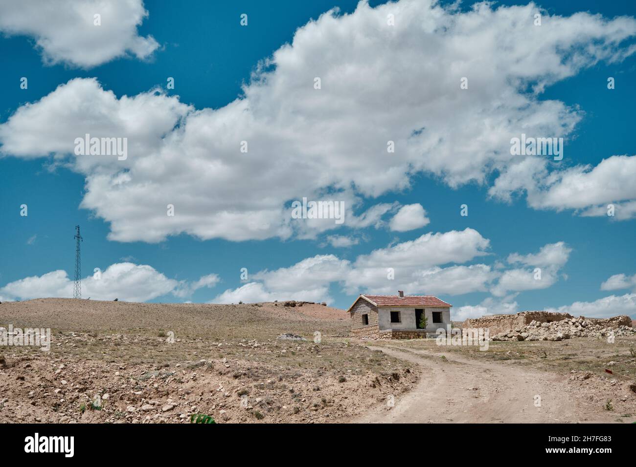Typisches Dorfleben in der Mitte der Türkei. Dreckiger Weg, ein einziges altes Steinhaus mit rotem Ziegeldach. Herrliche Wolkenlandschaft Hintergrund toget Stockfoto